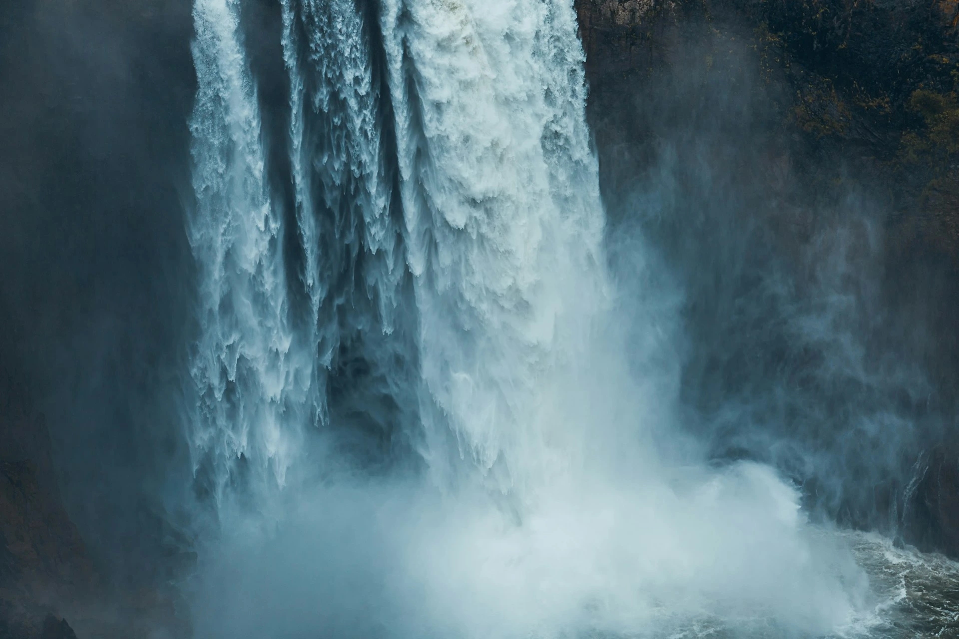 Powerful waterfall cascading down rocks, surrounded by mist and spray, creating a dynamic and serene atmosphere.